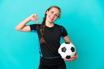 Young English woman isolated on blue background with soccer ball and proud of himself
