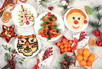 Fototapeta na wymiar Christmas new year dishes, traditional festive salad with tiger and santa claus, symbol of the year, edible veggie trees made of vegetables and fruits, food design idea, fir branches and decorations 