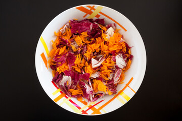 Salad with carrots on black table, top view
