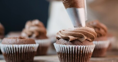 Fresh chocolate cupcakes in paper forms. Filling middle of muffins with chocolate cream or condensed milk. Close up