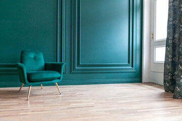 Beautiful luxury classic blue green clean interior room in classic style with green soft armchair. Vintage antique blue-green chair standing beside emerald wall. Minimalist home design