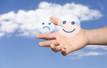A sad and joyful face in the hand. Choosing between the negative and the positive in a person's life