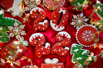 Banner for Christmas and New Year gingerbread cookies numbers 2022, snowflakes, Santa hat, Christmas trees, garlands on red silk fabric background