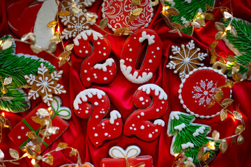 Banner for Christmas and New Year gingerbread cookies numbers 2022, snowflakes, Santa hat, Christmas trees, garlands on red silk fabric background