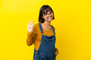 Young pregnant woman over isolated yellow background happy and counting four with fingers