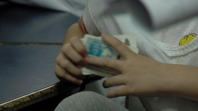 Hands of Schoolgirl Holding Blurred National ID Card in Classroom