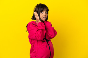 Young pregnant woman over isolated yellow background frustrated and covering ears