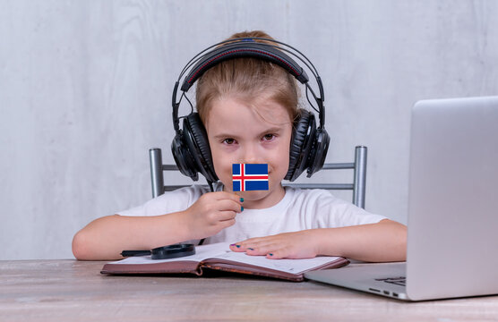School female child with Iceland flag. Child in headphones, with a book and laptop has lesson online