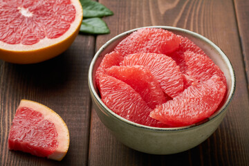grapefruit pieces in a bowl on brown background close up