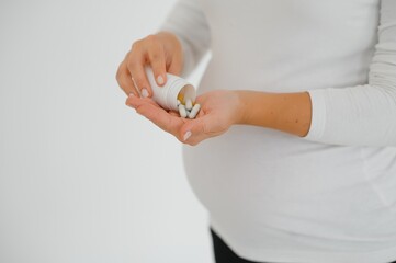 Obraz na płótnie Canvas Closeup photo of pregnant woman holding pills and medicine bottle