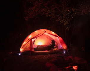 Smiling couple lying in tent illuminated at night