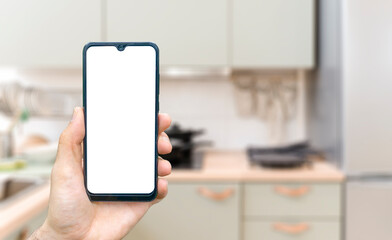 Kitchen background with hand with phone. Blurred home kitchen with blank smartphone screen. Online grocery ordering concept, online food shopping.