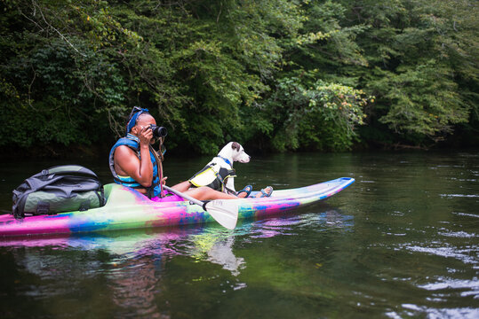 Woman with dog in kayak on river