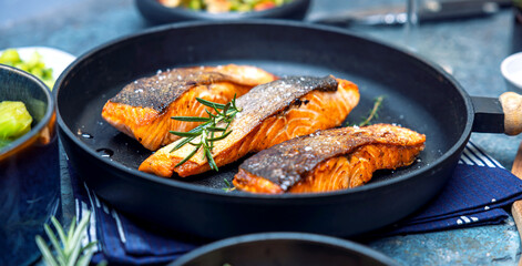 Gebratener Lachs serviert in einer Pfanne mit Beilagen Salat.