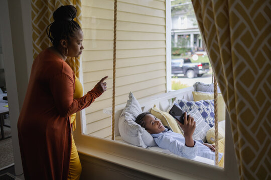 Mother talking to teenage daughter sitting on sofa on porch