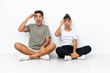 Obraz premium Young mixed race couple sitting on the floor isolated on white background intending to realizes the solution while lifting a finger up