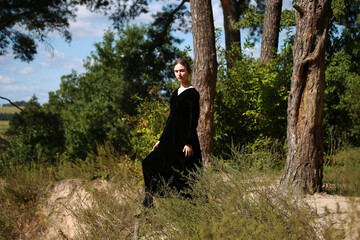 Woman in black dress in the forest in summer