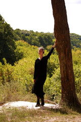 Woman in black dress in the forest in summer