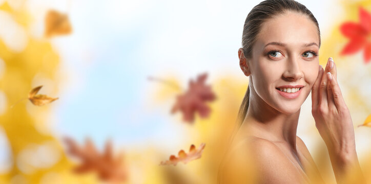 Beautiful young woman with autumn leaves on white background with space for text