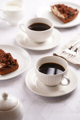 sweet breakfast - two white porcelain cups with coffee drink on a white saucer, piece of brown cake