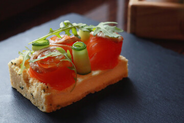 Tasty salmon sandwich on dark background
