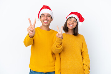 Young mixed race couple celebrating Christmas isolated on white background smiling and showing victory sign