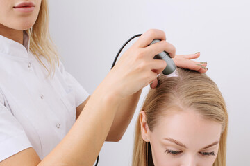 Doctor diagnoses the structure of the hair. Consultation with a trichologist
