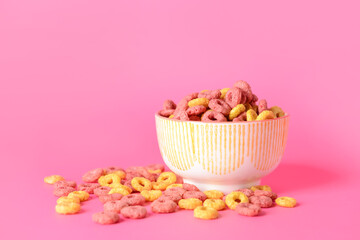 Bowl with crunchy corn flakes rings on color background