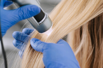 Doctor diagnoses the structure of the hair. Consultation with a trichologist