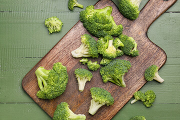 Board with healthy broccoli cabbage on color wooden background