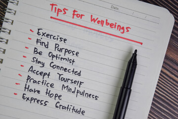 Tips For Wellbeings write on a book isolated on Wooden Table. - obrazy, fototapety, plakaty