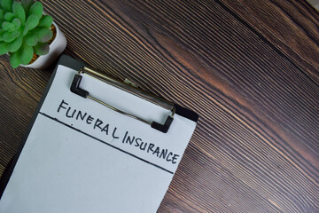 Funeral Insurance write on sticky notes isolated on Wooden Table.