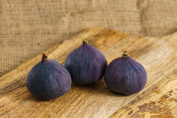Three fig fruits on old wooden chopping board.
