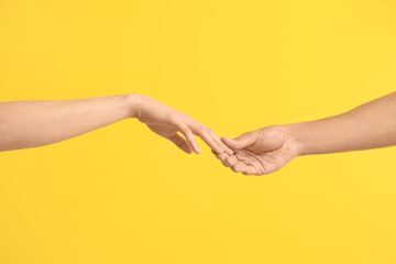 Man and woman touching fingers on yellow background