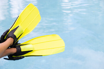 Female legs in flippers on blue water background. Concept of summer vacation. © Vitalina
