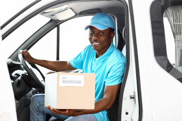 African-American courier of delivery company sitting in car