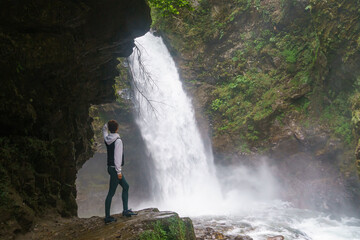 Young woman standing in front of waterfall. People travel enjoying nature, break from city