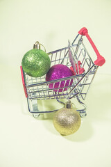 Christmas ball in the small metal shopping cart on the yellow background