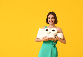 Young woman with many rolls of toilet paper on color background