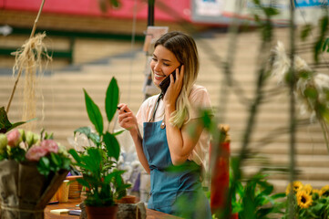 Florist talking with client on the smartphone and taking an order in a flower shop