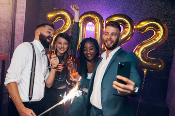 Happy group of friends celebrate New Year's Eve and taking selfie with a smartphone