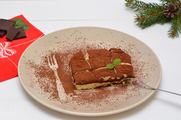 tiramisu on a plate and branches of a christmas tree