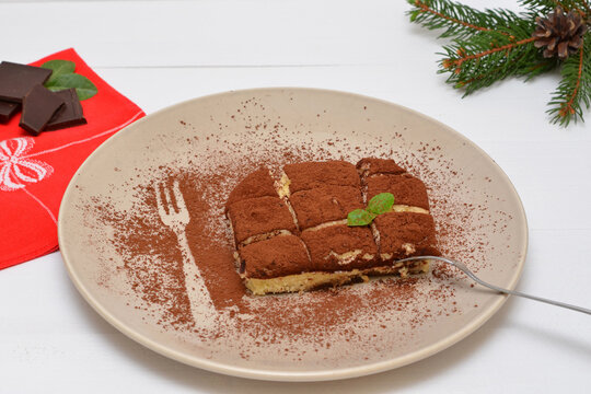 tiramisu on a plate and branches of a christmas tree