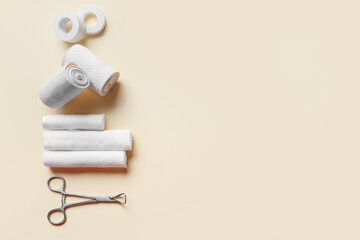 Bandage rolls, medical plaster, cotton buds and surgical tool on color background