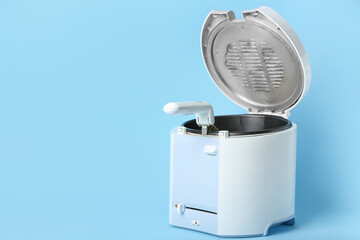 Modern deep fryer on color background