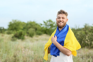 Fototapeta premium Happy young man with Ukrainian flag outdoors