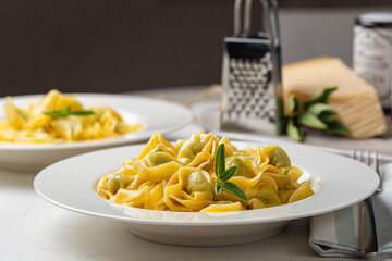 Lunch, tortelloni with spinach and ricotta.  Stuffed pasta stir-fried with melted butter and sage leaves. Parmesan cheese. Dark background.
