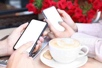 Women using mobile phones in cafe, closeup