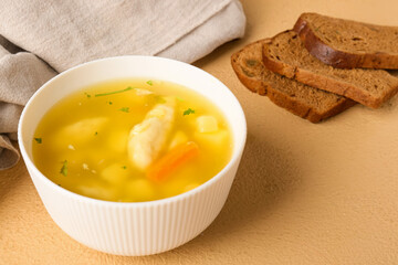 Bowl of delicious dumpling soup and bread on color background