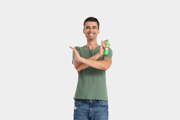 Young man with mosquito repellent on light background